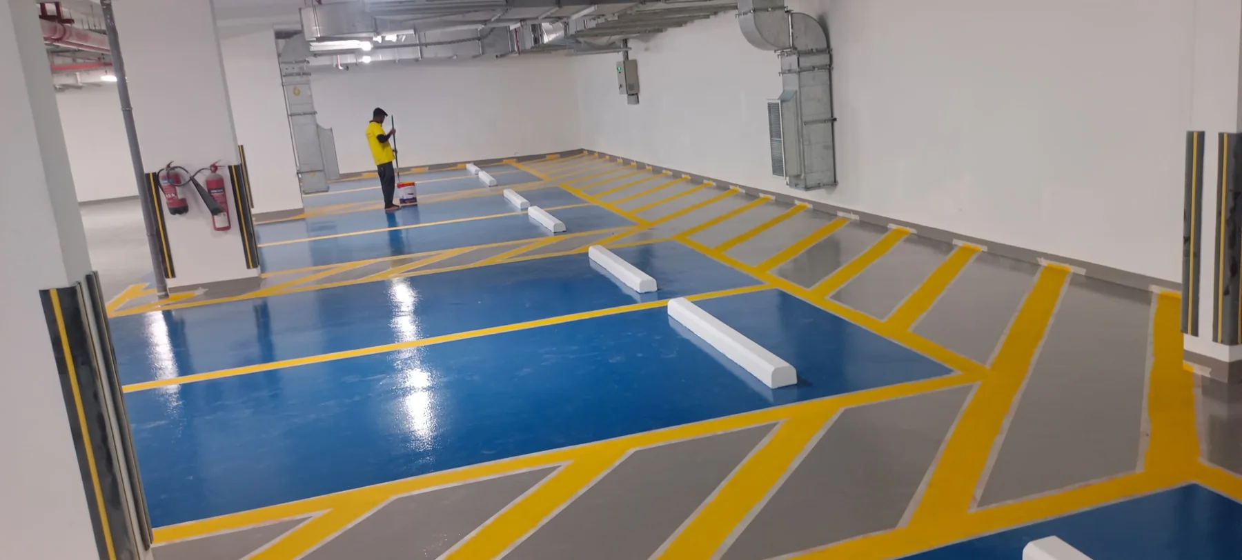 Completed blue and grey epoxy parking floor with yellow traffic markings
